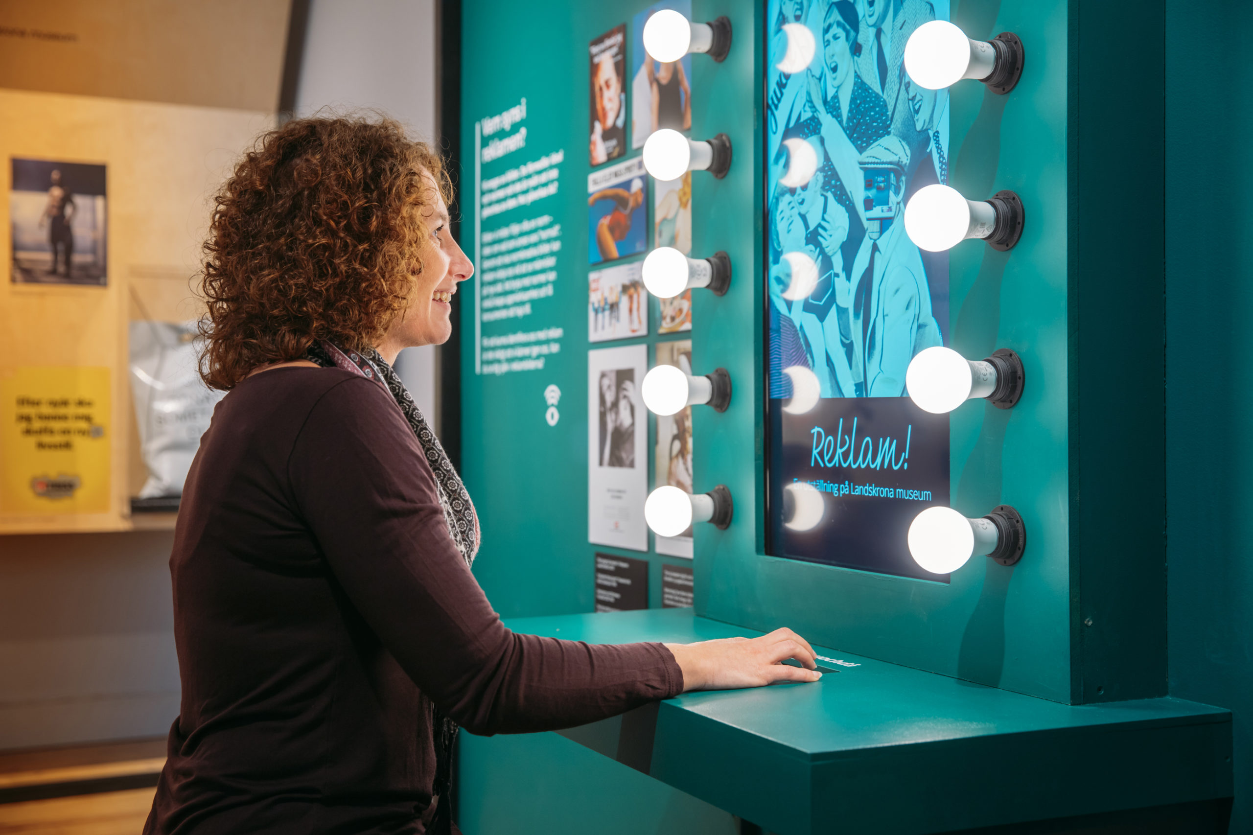 En kvinna står och tittar på utställningen Rum för reklam på Landskrona museum