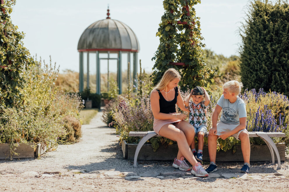 Tre barn sitter på en bänk i Tycho Brahes trädgård