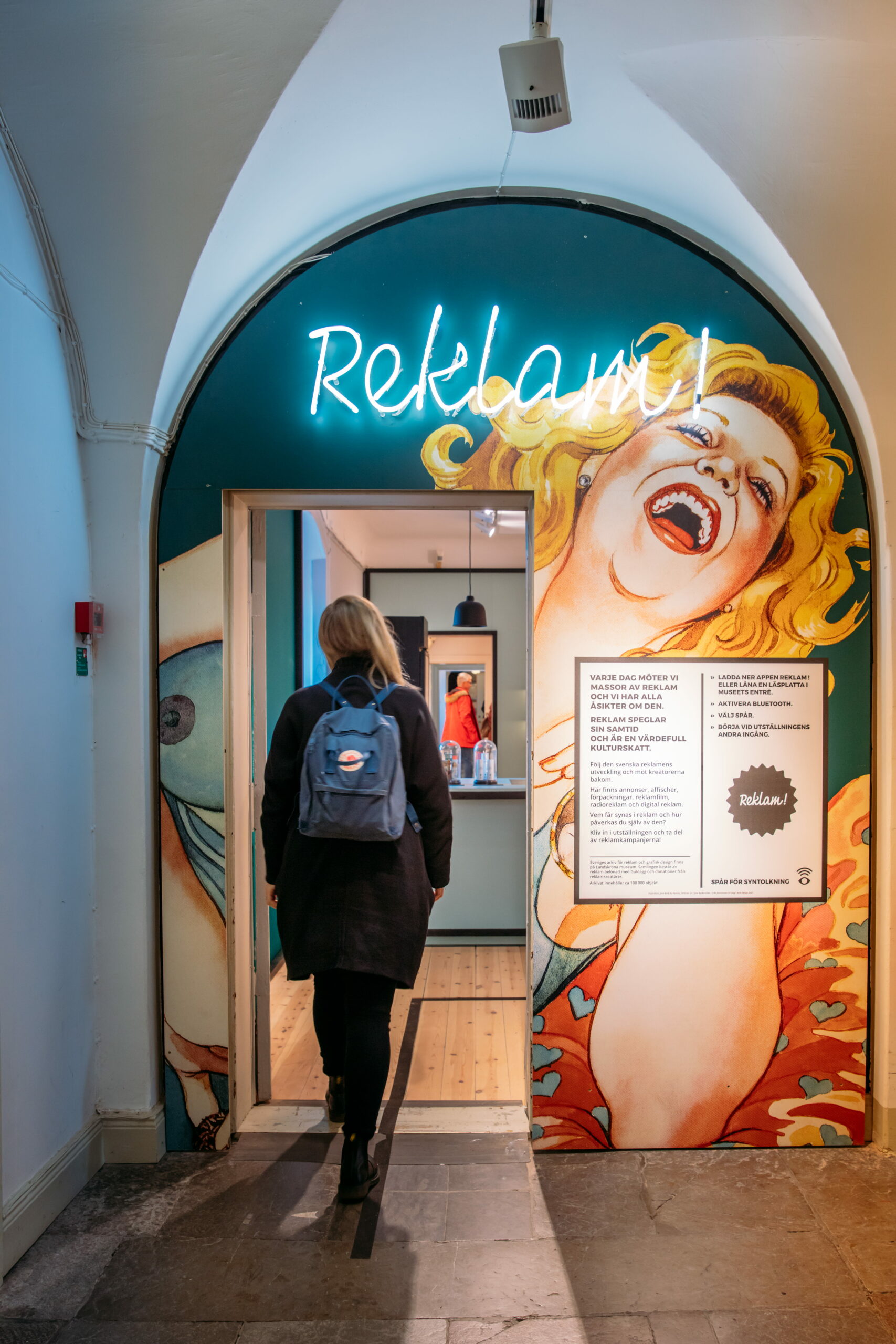 En kvinna går in till utställningen Reklam på Landskrona museum