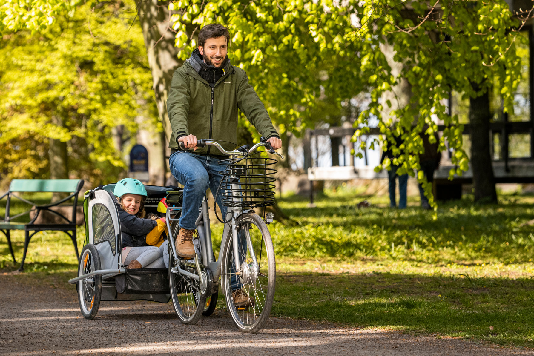 En man cyklar och drar en vagn efter sig med två barn
