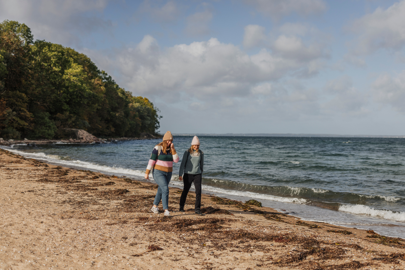 Två kvinnor promenerar längs stranden på Ven