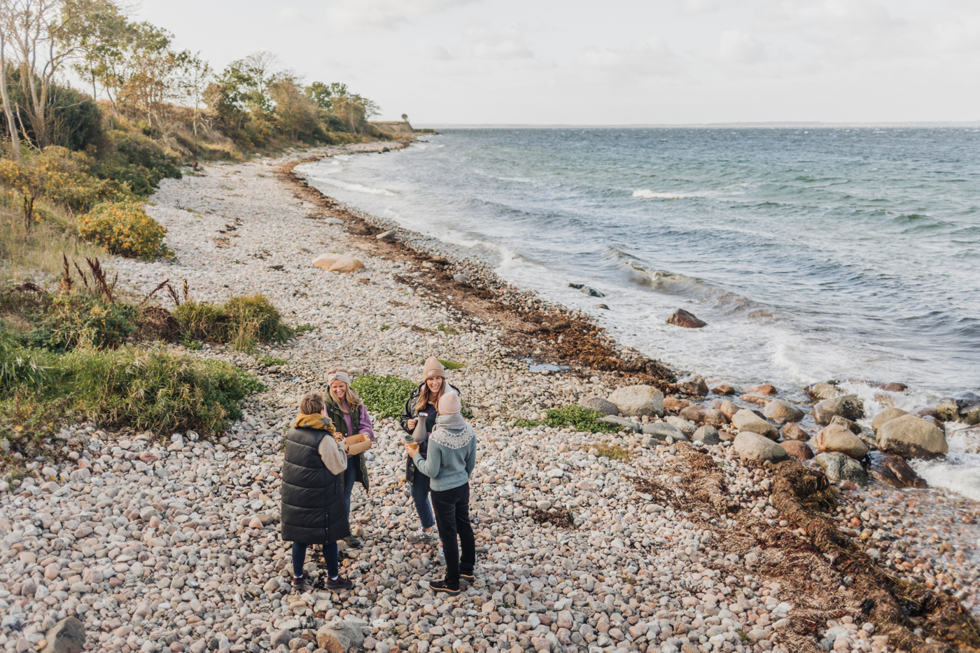Fyra kvinnor står på en strand och pratar