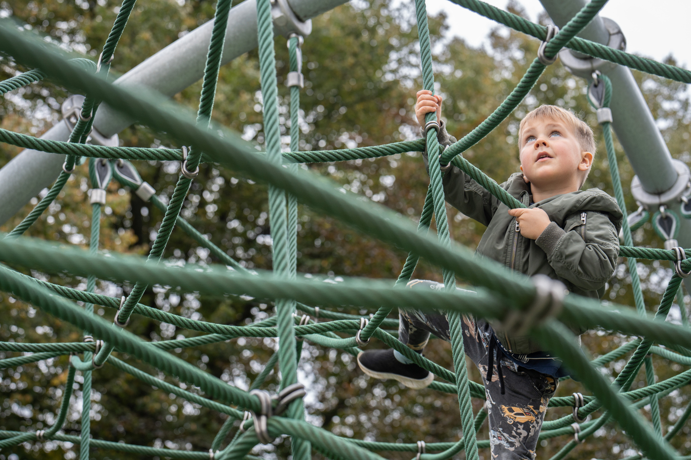 A boy is climbing a net on a plyground