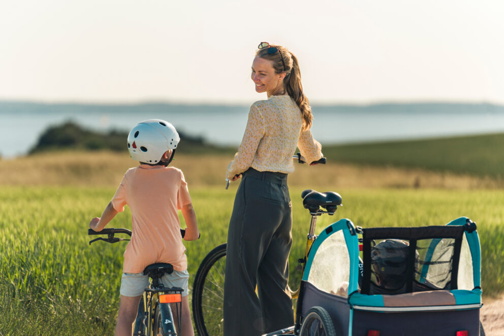 En mamma och två barn med cyklar och kärra