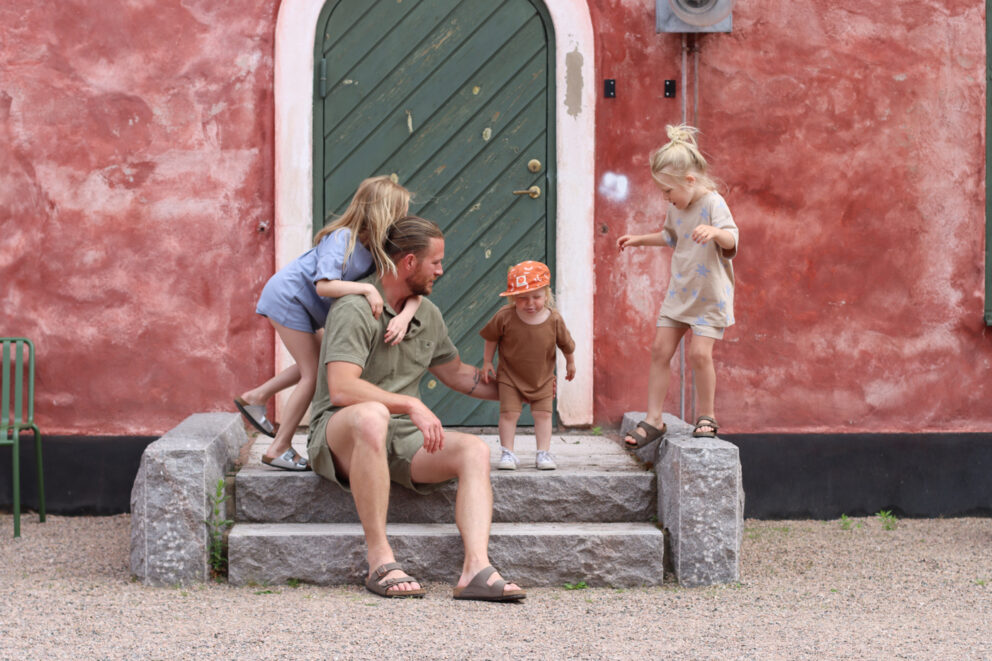 En pappa och tre barn sitter på en trappa vid Citadellet