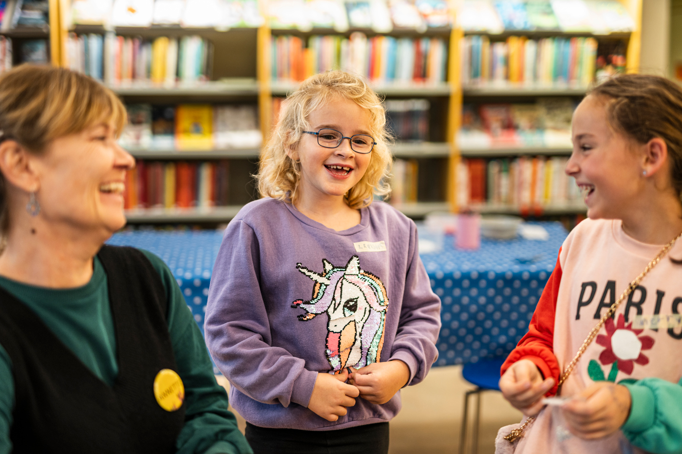 Två flickor och en kvinna sitter på ett bibliotek