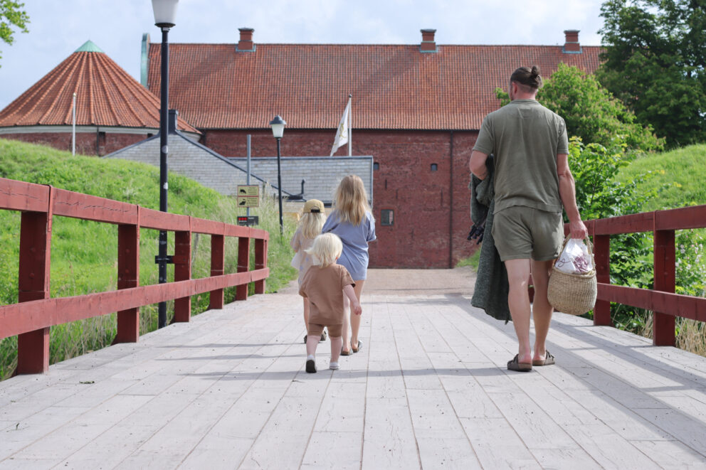 En man och tre barn går över bron till Landskrona slott