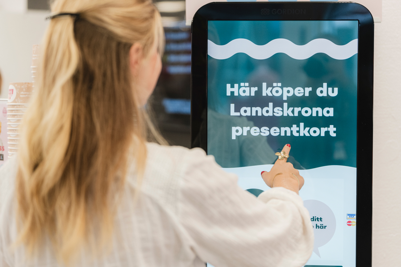 En person står och köper presentkort vid en automat