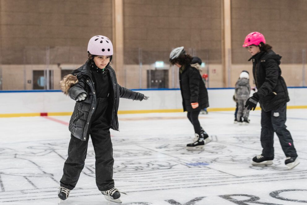 Några barn åker skridskor i en ishall