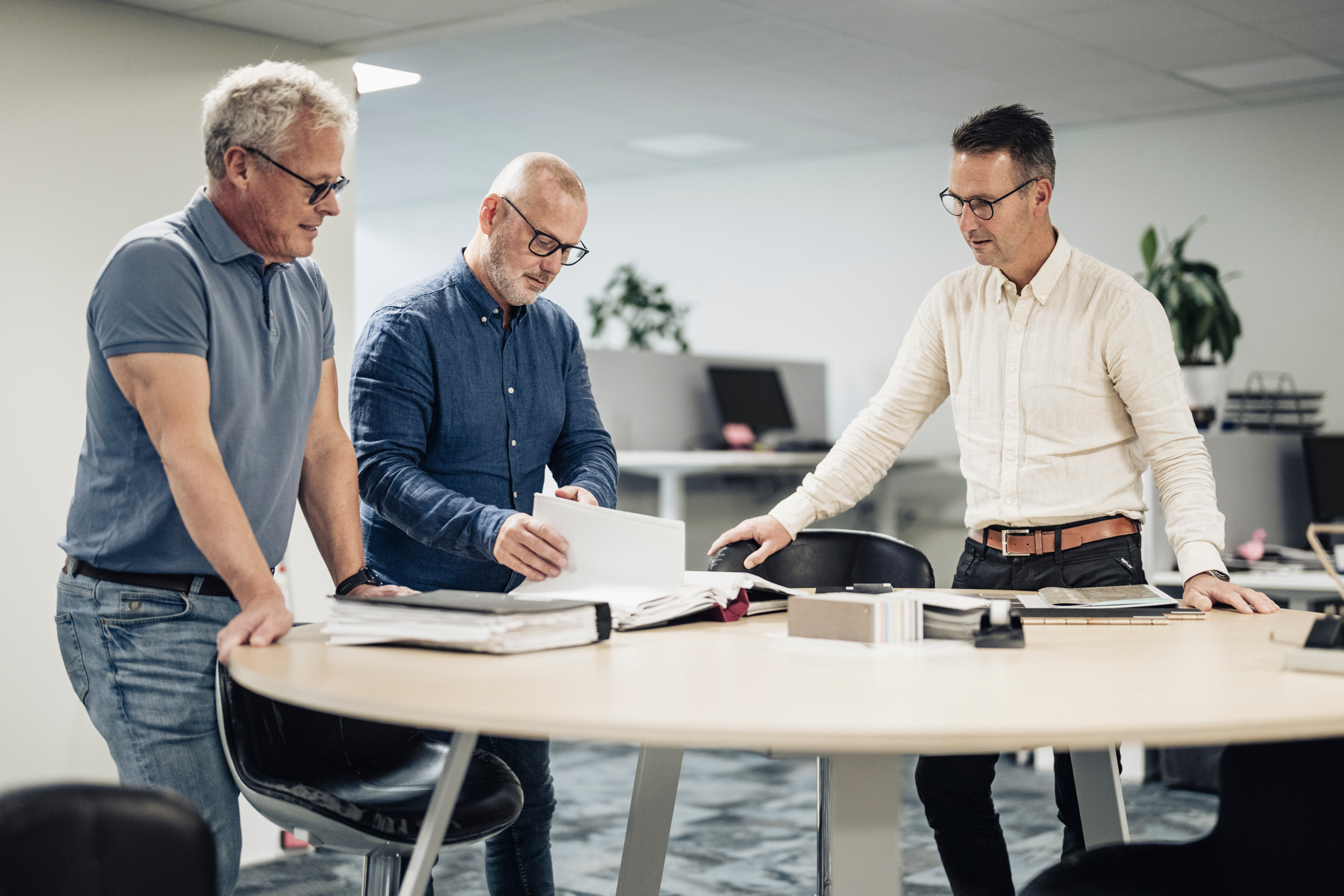 Tre män står runt ett bord