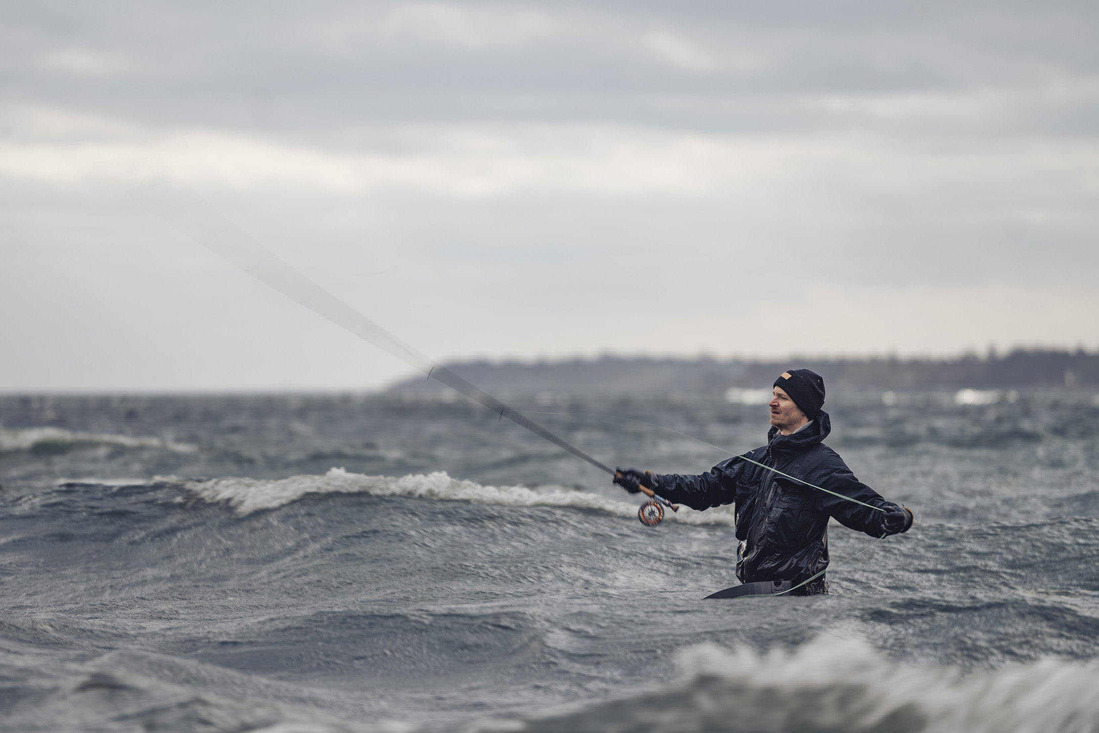 En man står i havet och fiskar