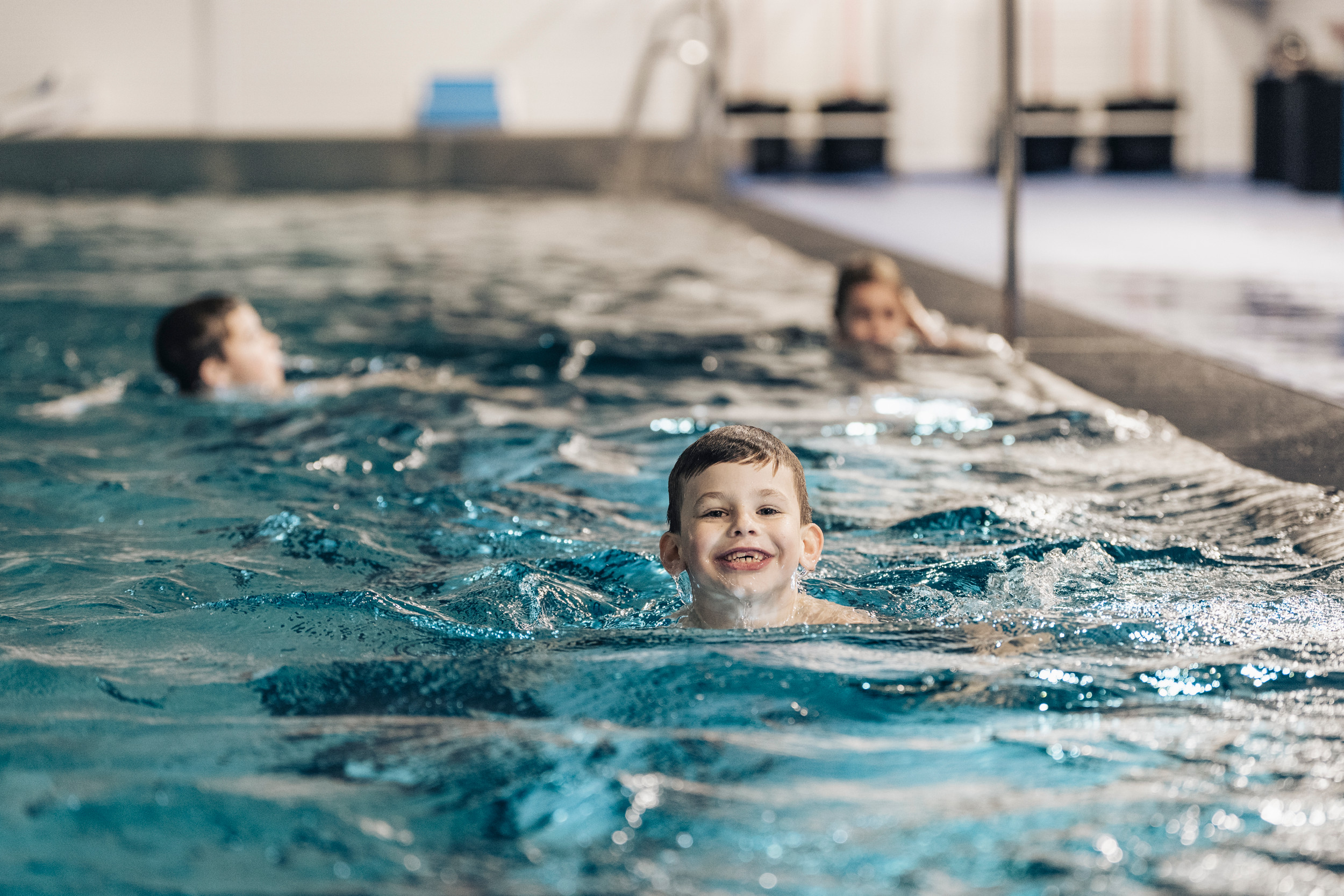 Tre barn simmar i en bassäng