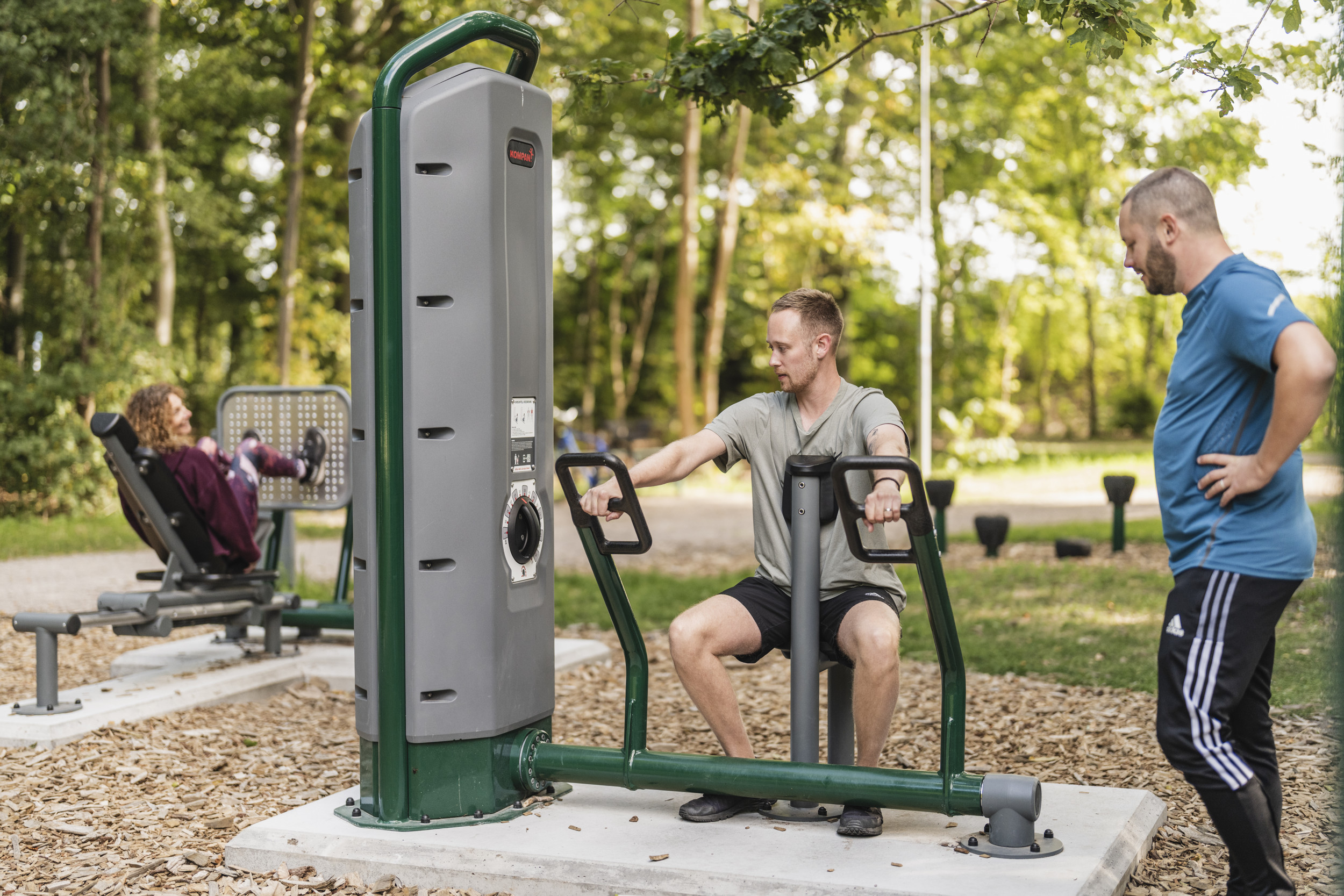 Tre personer tränar på ett utomhusgym